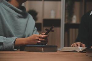 Two people sitting at a table with a bible and a cross photo