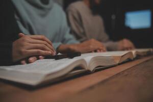 Two people are sitting at a table with an open book photo