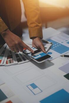 A person is using a tablet on a table with various design materials photo
