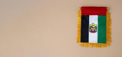 Small flag of UAE in beige background. Copy space. Mock up advertisement template. Tourism travel voucher with United Arab Emirates national symbol. Visit Dubai concept photo