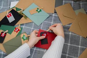 Number on craft envelopes notes with tasks before Christmas holidays. Female making kraft paper for handmade advent calendar Made with your own hands step by step DIY crafts do it yourself photo