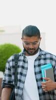 Handsome Indian Asian student walking after class in university campus. Vertical video