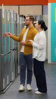 Young couple is viewing fridge in home appliances store. Vertical video