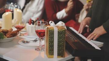 A group of people sitting at a table with a piano and a gift video