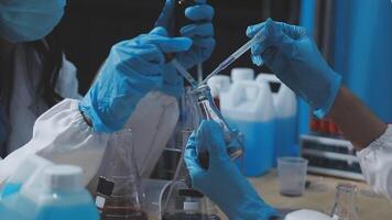 Two people in lab coats and gloves are working on something video