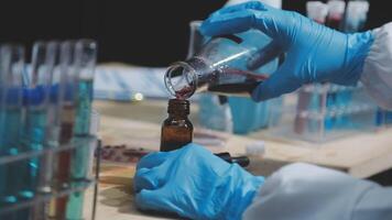 A person in a lab coat is pouring liquid into a bottle video