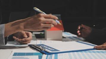 Two people sitting at a table with papers and pens video