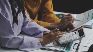 dois pessoas trabalhando em uma computador portátil e uma calculadora video