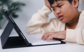 Boy using tablet for learning and stressed about online learning, Virtual internet online class from school teacher by remote meeting, Homeschooling and education concept. photo