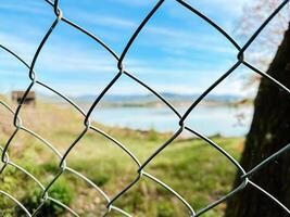 A chain link fence with a view of a lake photo