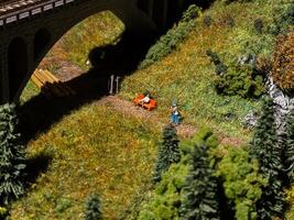 A man is walking on a path in a field with a toy train set photo