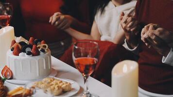 A group of people sitting at a table with a cake and wine video