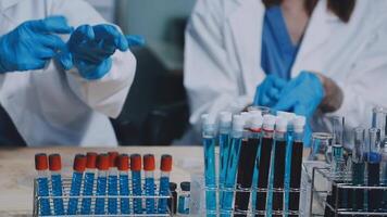 Two people in lab coats and gloves working on a table video