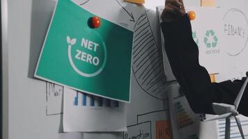 A man in a black jacket is holding a whiteboard with net zero on it video