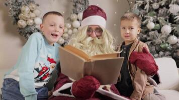 Santa claus entertaining children with a storybook while seated on a cozy sofa video