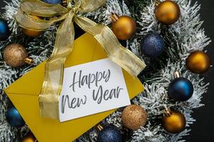 Christmas handmade wreath made of festive decorations with yellow envelope and paper note with HAPPY NEW YEAR text. Winter holiday celebration greeting card. top view photo