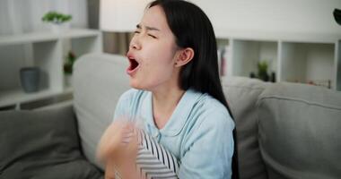Handheld high angle view shot, An attractive young woman is intently watching something on TV and shows signs of extreme excitement and joy while sitting on sofa in the living room at home. video