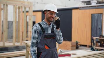 Engineer instructing worker near unfinished prefabricated modular house using walkie talkie radio set at factory video