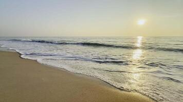 A beach with waves and the sun setting over the ocean video