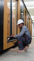 Worker using of foam when installing windows in prefabricated house. Vertical video