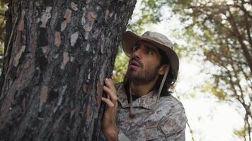 Scared Soldier Hides Behind The Trunk Of A Tree In The Mountains From The Enemy video