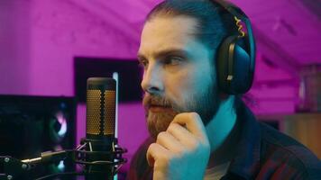 Puzzled thoughtful Caucasian influencer guy blogger player streamer man vlog contemplating cyber sport neon thinking gaming decision at home addict male gamer host play computer game blog idea thought video