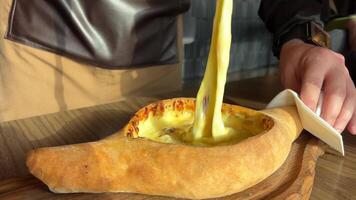 A man eats Adjarian khachapuri. Open pie with cheese and egg. video