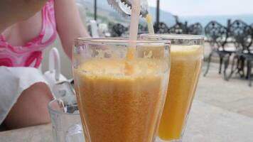 Appetizing orange juice swirls into a wave in a glass against the background of cut oranges. video