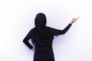 back view of muslim woman in black hijab pointing to something photo