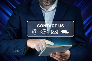 Contact us or Customer support. Businessman using tablet with email, call phone, mail, chat icons. Contact us, landing page, background photo
