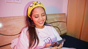 Lady sits in bedroom smiling while texting on mobile video