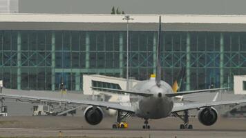 Unknown aircraft taxiing in front of terminal, rear view. Airliner on the airfield video