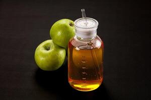 A bottle of liquid with two green apples photo