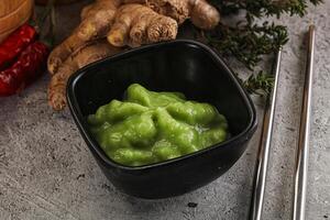 A bowl of green sauce next to a bowl of ginger photo