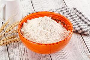 A bowl of flour next to a bowl of milk photo
