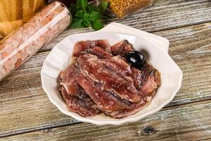 A bowl of meat and olives on a wooden table photo