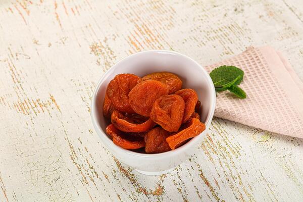 A bowl of dried apricots on a wooden table