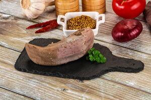 A meat on a cutting board with other ingredients photo