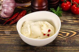 A bowl of ice cream sitting on a table next to a bowl of tomatoes and garlic photo