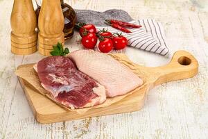 A wooden cutting board with meat and vegetables on it photo