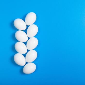 rows of eggs beautifully arranged on a blue background, top view, square format, space for text photo