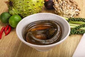 A bowl of worms sitting on a table next to a bowl of fruit photo