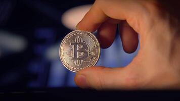 A closeup of a person holding a Bitcoin in a modern setting, highlighting tech and finance video