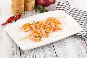 A plate with shrimp and vegetables on skewers photo