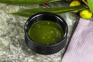 A cup of green liquid sitting on a table photo