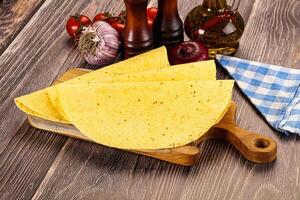 Three tortillas on a cutting board with tomatoes and spices photo