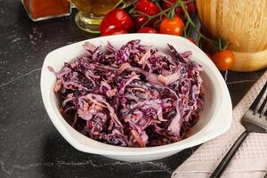 A bowl of red cabbage salad with a fork and knife photo