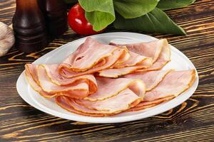 A plate of sliced ham on a wooden table photo