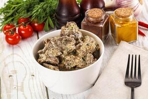 A bowl of meat and vegetables on a table photo