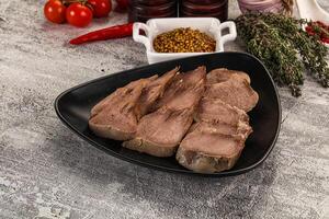 A plate of meat on a table with a bowl of spices photo